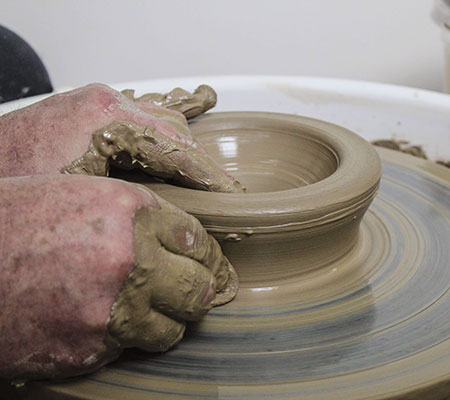 2 Before raising the walls, press in on the outside of the base of the clay so the walls will stick out a bit from the bottom.