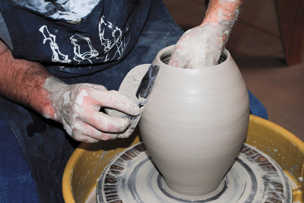 2 Smooth and compress the surface of the pitcher body using a metal rib on the outside, while supporting the curve on the inside.