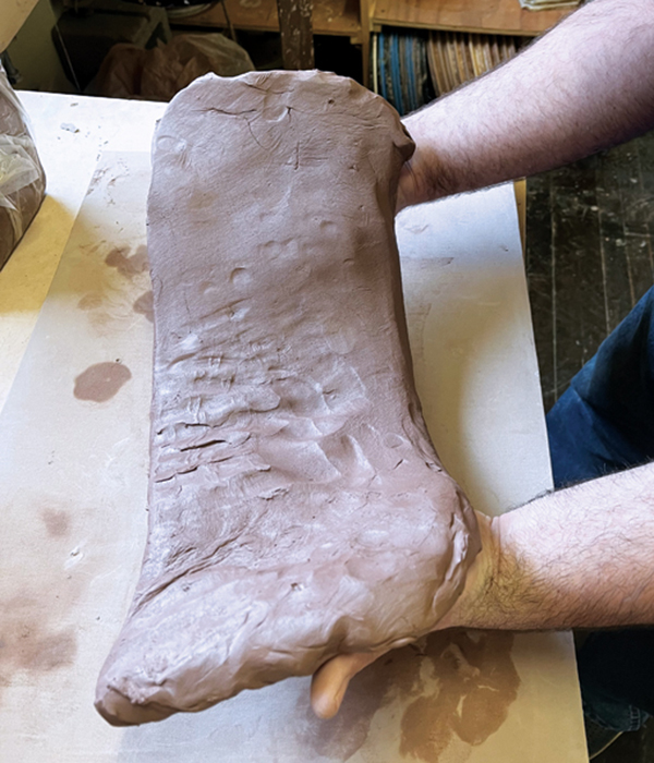 4 Lift one side of the slab, supporting the clay from below with open palms.