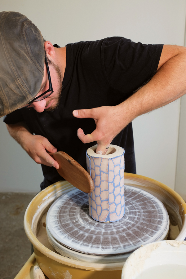 Applying the sliced cane to the outside of a thick thrown cylinder and paddling to ensure a secure attachment.