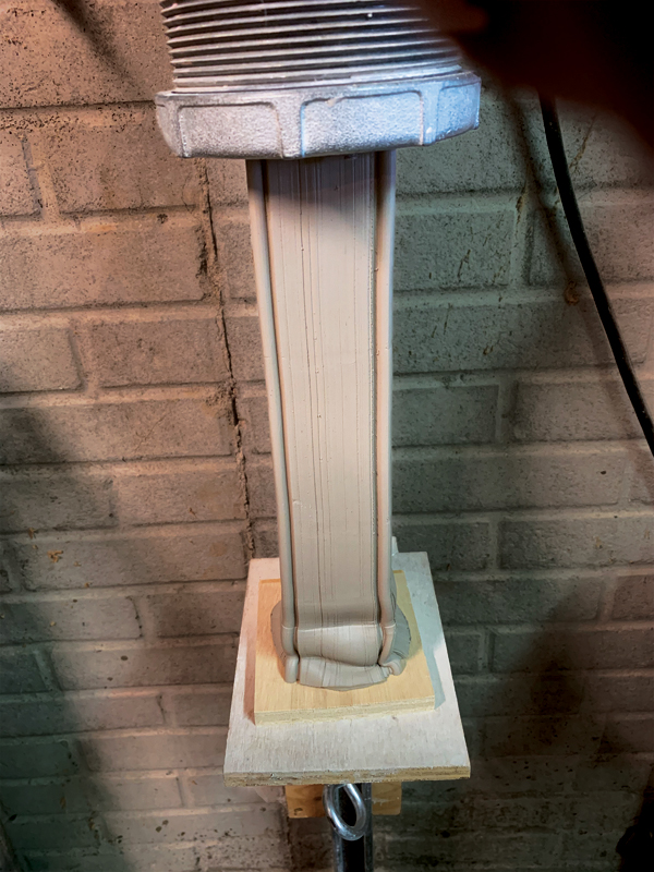 6 Press the bat up against the clay tube while extruding to shape the bottom.
