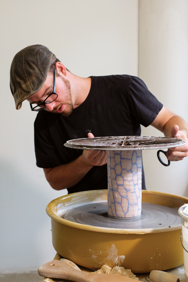 Attaching the cylinder to a separately thrown base. Leaving the cylinder attached to the bat during this process keeps the surface of the colored clay from being smearing, because the bat is handled rather than the piece.