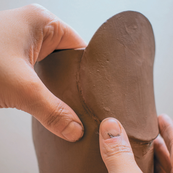 8 Cut out an opening for the spout, then cut a large, circular slab spout and attach.
