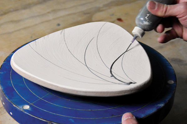 9 Starting in one corner, slip trail the stems of the grass pattern in a fan shape across the plate.