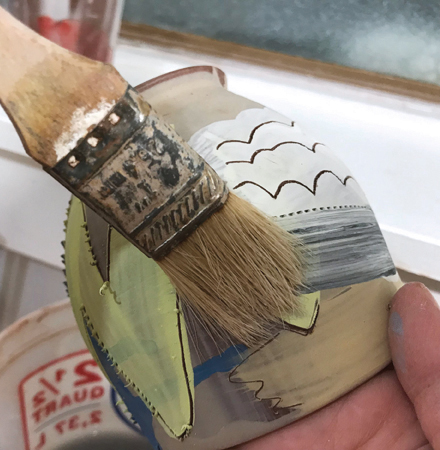 9 Use a small paintbrush to carefully clear away the clay burrs created when drawing the sgraffito decoration.
