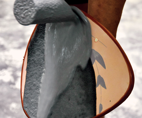 11 Pour an ash glaze over the face of the plate using a ladle.