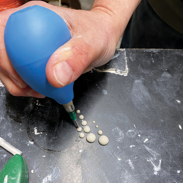 1 Fill a slip trailer with liquid clay slip, then test the flow of the applicator on a table.
