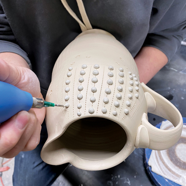 2 Carefully apply slip dots to the surface of the piece, following the lines that were drawn with the tracing wheel.