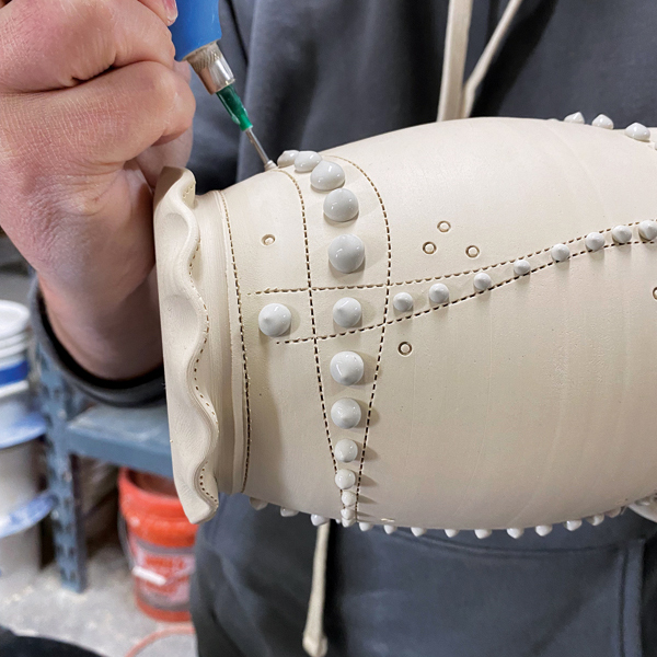 3 Continue to add dots in various sizes along the lines and in between the lines to create motion along the pot.