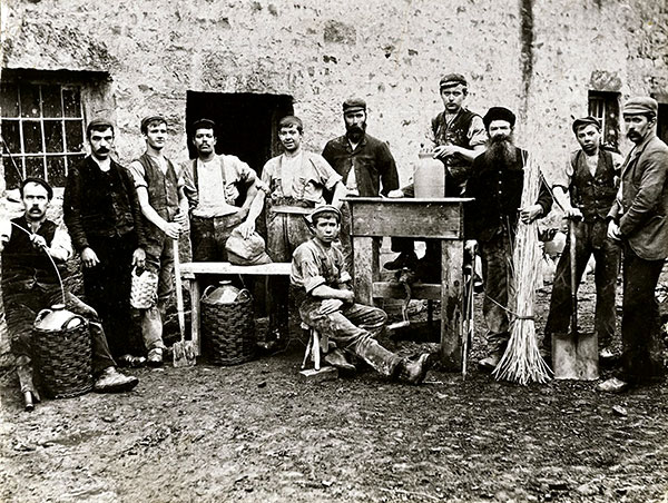 2 Workers at Waterside Pottery sometime around 1900. Notice the hand crank on the wheel, which allowed pots to be made when the steam engine wasn’t running. Left to right: Jack Lee, Squire Taylor, unknown, unknown, unknown, Harry Bateson, unknown, William Taylor, unknown, Frank Bateson. Seated: unknown. 