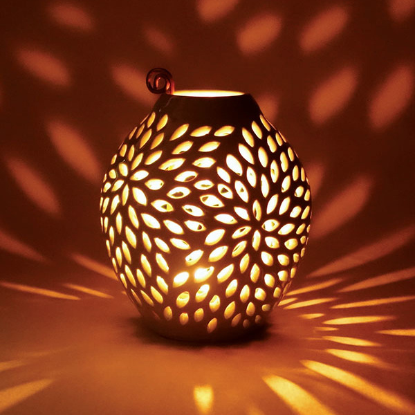 Pierced vase with lit tealight.