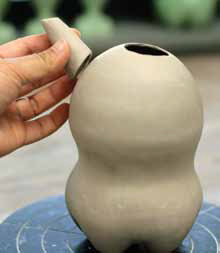 5 Adjust the size of the hole at the top of the pot and make a short spout. Shape it to fit the form, then attach it.