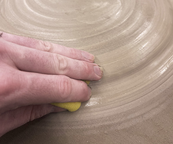 6 Flip the mold over and compress a clay slab onto the convex curve of the mold.