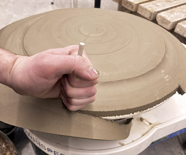 7 Remove excess clay with needle tool.
