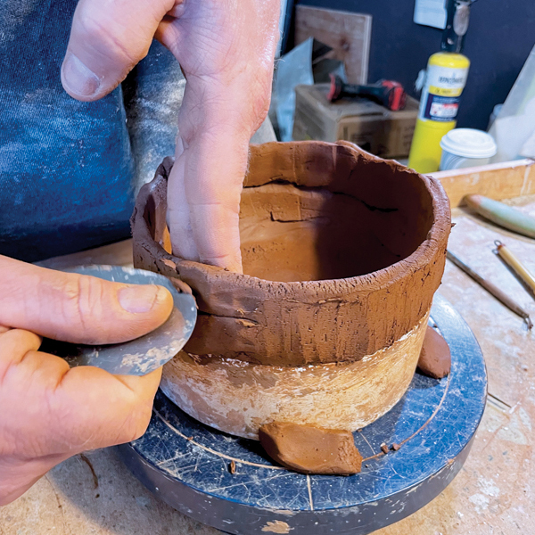 6 Next, use the rib to scrape the coils in an upward motion to smooth and shape the wall.