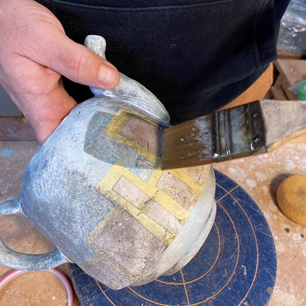 3 After bisque firing, liberally coat the whole piece with black underglaze wash, adding it all over and into the cracks and textures.