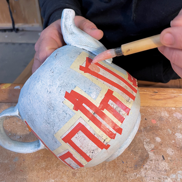 5 Use automotive pinstripe tape to block off spaces where you want to add underglaze, then paint on the underglaze.