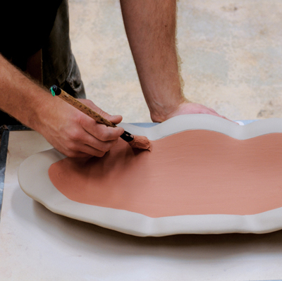6 Apply a white base coat of slip to the bottom and the rim. Apply a thick colored slip to the interior using a soft brush.