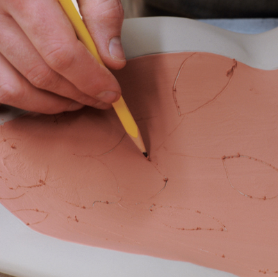 7 Sketch a design onto the interior with a dull pencil. Press lightly so that you don’t scratch through to the clay below. 