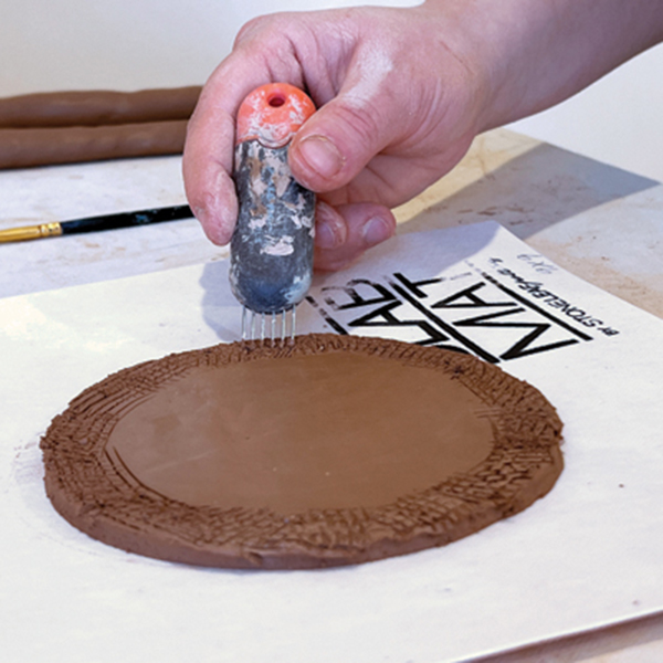 1 Score the slab, then add a little bit of water or slip to the scoring so you create a glue for your coil to stick to.