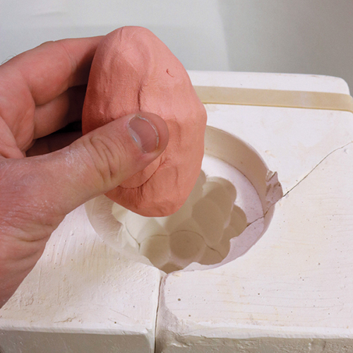 9 Press a ball of clay into the plaster mold to form the rough shape of the reamer.