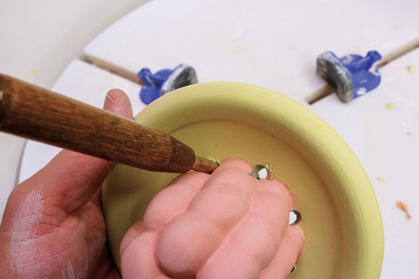 13 Using a hole-cutting tool, punch drainage/strainer holes through the top section. Hold a finger on the reverse side to limit tearing. 