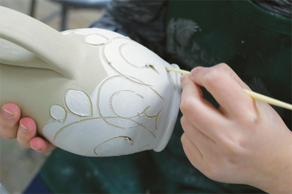 8 Outline the motifs (cacti on my form) and draw swirls or other shapes that compliment the composition using a plastic sculpting tool.