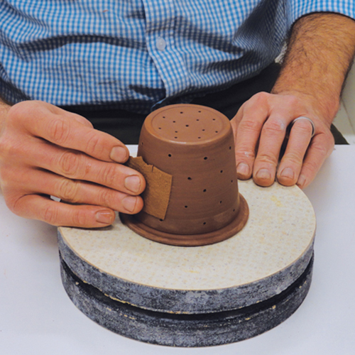 6 Use a needle tool to create multiple small holes in the infuser. Smooth the clay with a chamois.