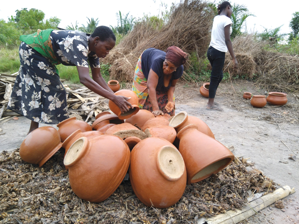 5 Potters in Vume work collaboratively to gather combustibles and stack their greenware pots in preparation for a firing, 2018.