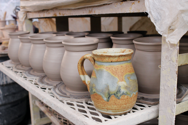 5 Shelf of newly thrown mugs shown with a finished mug at Dirtworks Pottery in Seagrove.