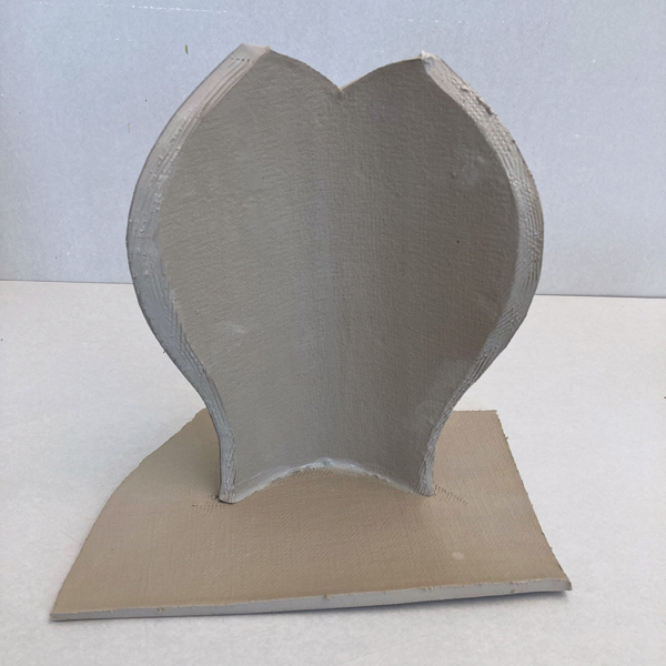 3 Curve the bottom of the form, score the edge, apply slip, and attach it to a slab.