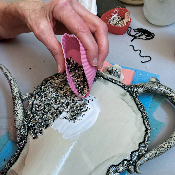 15 On the back, paint glue over an area and sprinkle beads. 