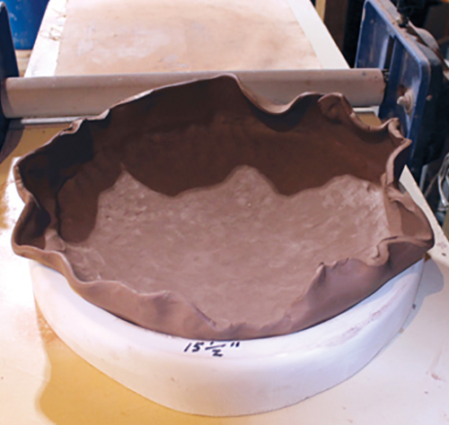 2 Roll out a slab to ⅜ inch thick and press it into the mold with your hands.