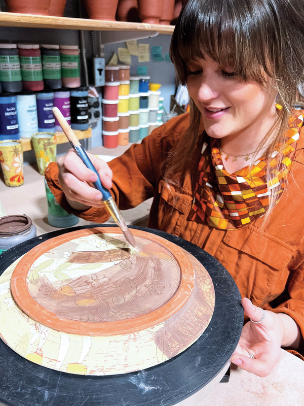 3 Lakyn Bowman applying underglaze wash to a dinner plate, 2022.