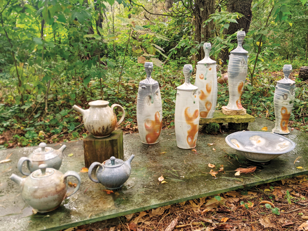 9 Porcelain and stoneware wood-fired teapots, bottles, and serving bowl on display during the 2022 Michiana Pottery Tour.