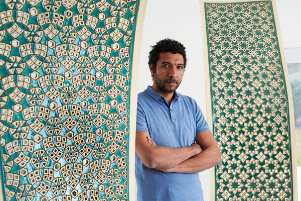 1 Ibrahim Said with his work On the Bank of the Nile, 8 ft. 4 in. (2.6 m) in height, white earthenware, pine, maple, walnut veneer, 2021. Photo: Dhanraj Emanuel. 