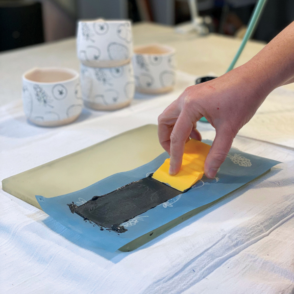 2 Use the squeegee to spread the underglaze over the image, making sure to apply the color evenly. 