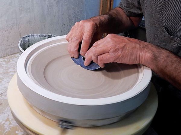  19 With the mold placed on the wheel, turning the wheel and ribbing to refine the face of the plate. 