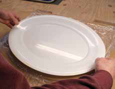 3 Lightly drape a dry cleaning bag over the trimmed slab and carefully place the right-side up platter on the plastic, guided by your fingers.