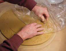 5 The area between the foot imprint and the edge of the slab defines the area to decorate. Lay plastic on the clay before pressing stamps.