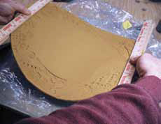 7 Lift the decorated slab with a pair of paint stirring sticks in each hand and transfer it to the plastic-covered tray and carefully align it.