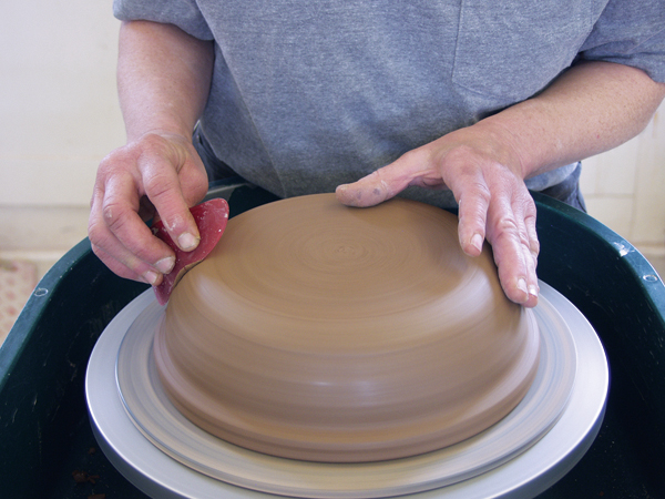 3 Turn the leather-hard pot over and trim it to round out the transition from floor to wall. Use a rib to smooth the pot.