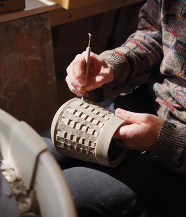 20 A student uses a hand tool to work on an in-process ceramic vessel at the Haystack Mountain School of Crafts. Photo: Dan Rajter.