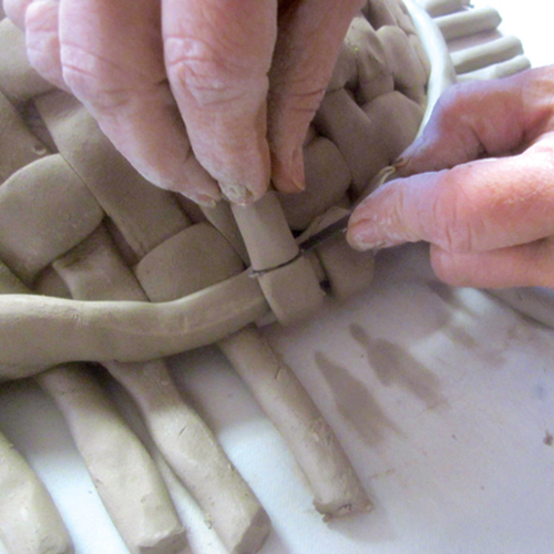 5 Pull the woven coils up and around the outer edge of the attached rim coil, then cut away the excess with a fettling knife.