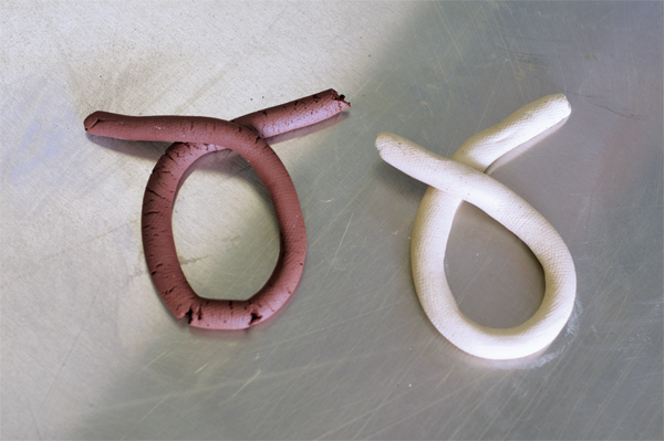 1 These two clay coils show the workability of the clays. The dark clay is a red stoneware clay just mixed compared to an aged porcelaneous body. Notice the cracks in the red stoneware coil versus the smooth quality of the white body. 