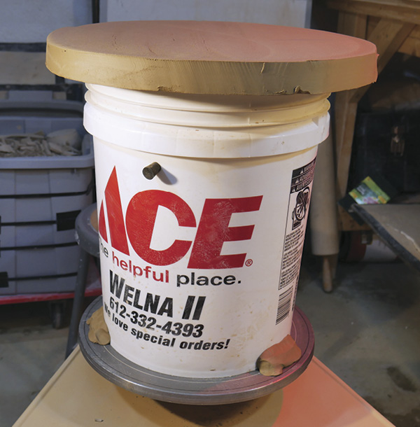 3 Center the bucket on the wheel head and secure with clay wads.