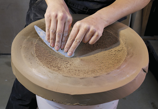 4 With the rubber plug out, stretch the clay downward with a metal rib to form the mold.