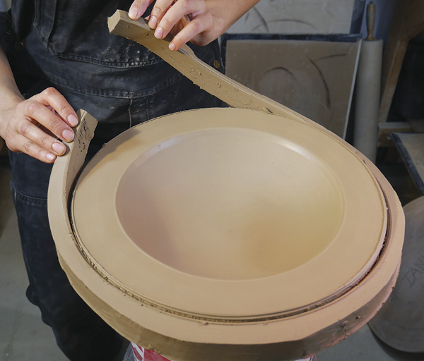 6 Once the concave form is refined, trim off the excess clay with a needle tool, leaving about 2 inches (5 cm) that will act as a “foot.”