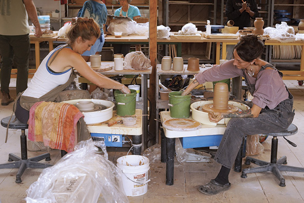 Two participants working on the wheels in the ceramics studio during the workshop, “Exploring Native Materials,” taught by Nathan Willever, 2024. Photo: Dan Rajter. Haystack Mountain School of Crafts, Deer Isle, Maine.