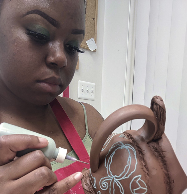 2 Ashlyn Pope in the studio, trailing slip on a mug.